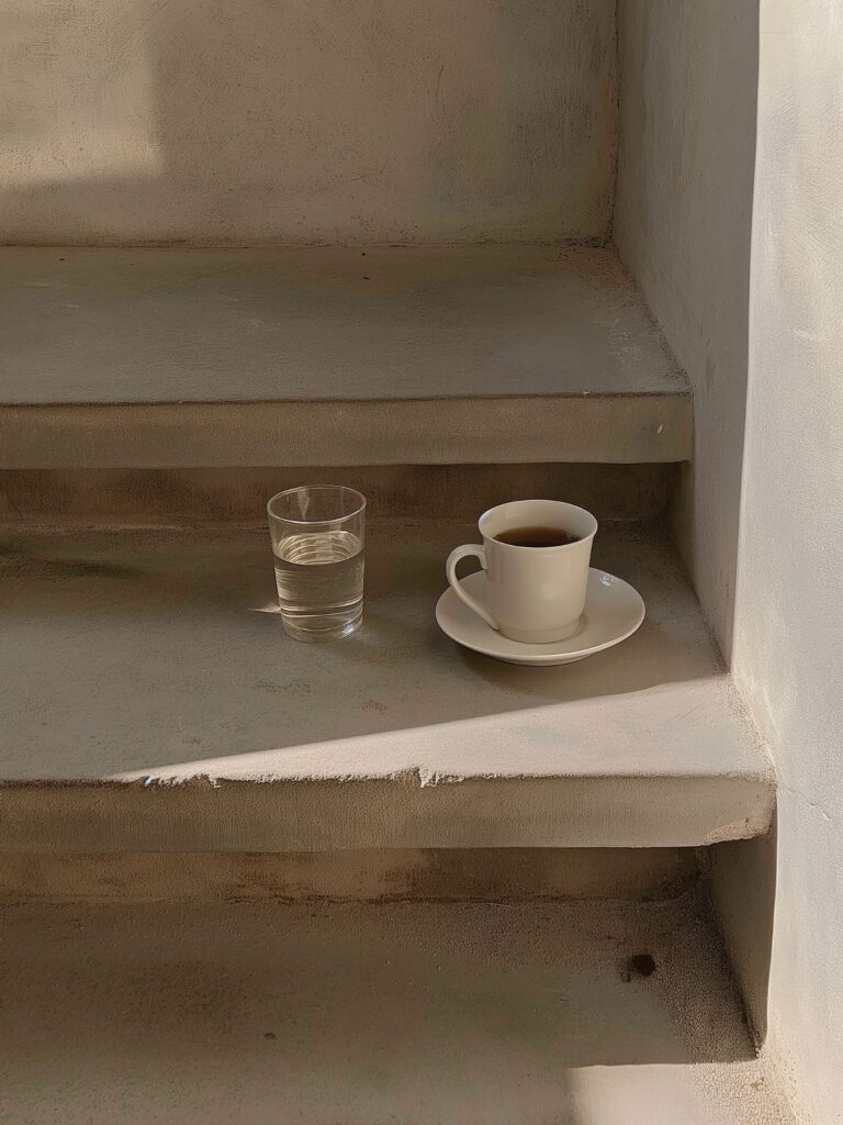 Ein Wasserglas und eine Kaffeetasse auf einer Steinstufe